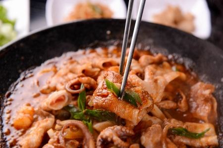 Stir-fried webfoot octopus and pork belly on plate, with chopsticksの写真素材