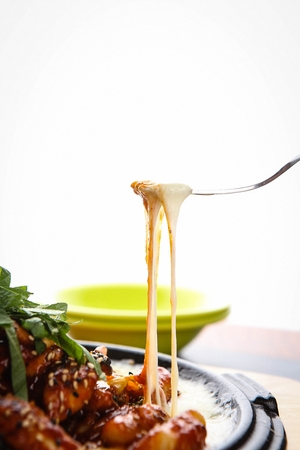 Stir-fried chicken and cheese with perilla leaves, on iron plate with fork