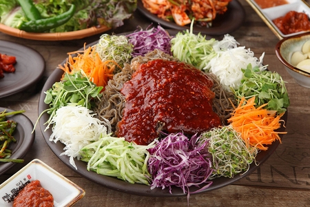 Spicy buckwheat noodles with carrots, cabbage, cucumber and sprouts in bowlの写真素材