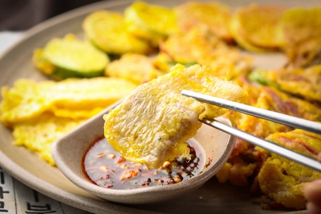 Chopsticks grabbing assortment Korean pancakes served on plate with soy sauceの写真素材
