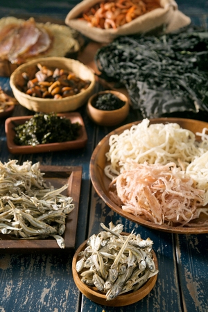 Dried snacks served on wooden plate and in wooden bowlの写真素材