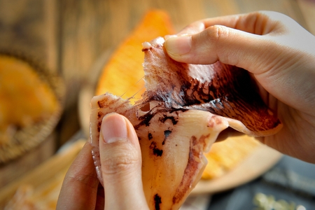 Hand grabbing grilled squidの写真素材