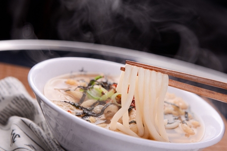 Udon Noodles with fried bean curd and seaweed flakes served in bowl with chopsticksの写真素材