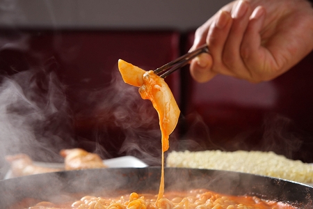 Spicy Rice Cake cooked on the spot with chopsticks grabbing spicy rice cake served on panの写真素材