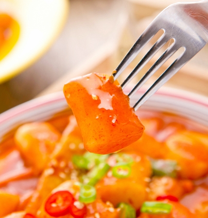 Spicy Rice Cakes with chili peppers with sesame seeds on top served in bowlの写真素材