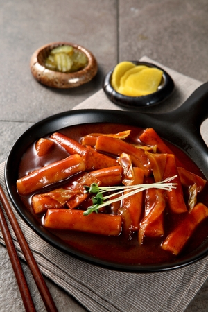 Spicy Rice Cake with radish sprouts and pickled radish served on plate with chopsticksの写真素材