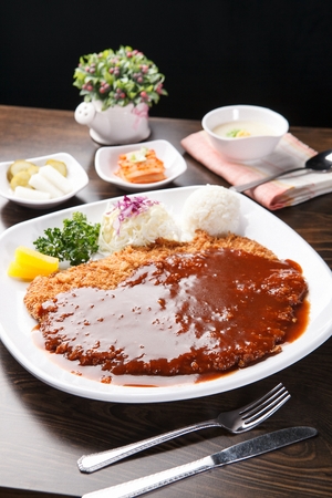 Pork Cutlet with Sauce and Salad Served on Plate with Fork, and Knifeの写真素材