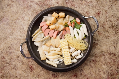 Spicy Rice Cake with ramen noodles ingredients with dumplings and sausage seerved on panの写真素材