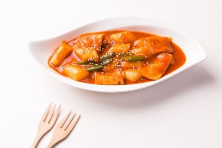 Spicy Rice Cake with sesame seeds and spring onion served in bowl with forkの写真素材