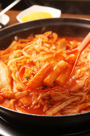 Spicy Rice Cake with Cabbage and fried vegetables served on pan with spoonの写真素材