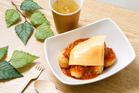 Shrimp balls with cheese on top and sauce served in bowl with drinkの写真素材