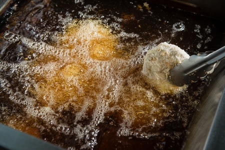 Croquette being fried on a fryerの写真素材