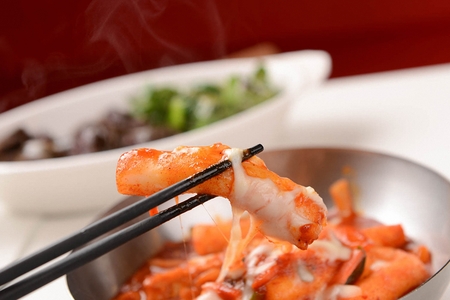 Cheese Spicy Rice cake served in bowl with chopstickの写真素材