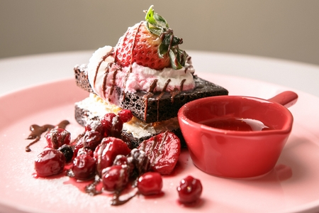 Strawberry Brownies with Chocolate Syrup on top and Pomegranate served on plateの写真素材