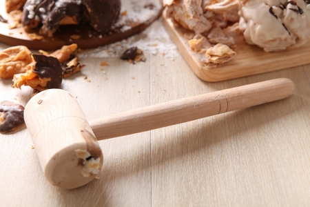 Hammer to break round snowball pastry on top of wooden table
