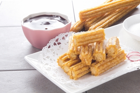 Churros with sugar and jam served on plateの写真素材