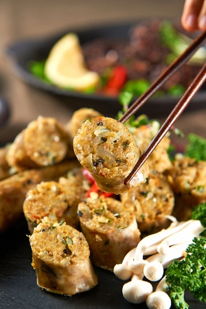 Chopsticks grabbing blood sausage with curry inside served on plate