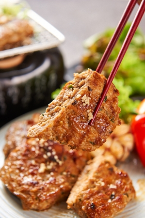 Grilled short rib patties with pine nuts on top served on plate with chopstickの写真素材