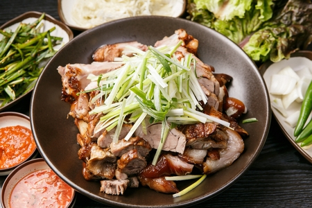Pig Feet with seasoned onions on top with lettuce, vegetables, soybean Korean paste served on plateの写真素材