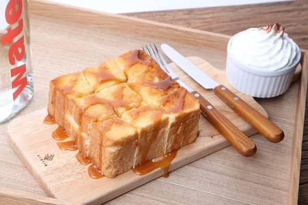 Honeybread with syrup poured on and cream served on plate with knife and fork