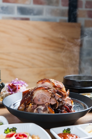 Chopsticks grabbing pig feet with sesame seeds on top served in bowl with garlic, Korean soybean paste, onion, and saladの写真素材