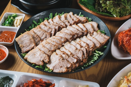 Korean cuisine Suyuk - boiled pork slices with chives on porcelain bowl and side dishの写真素材