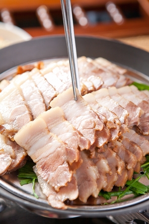 chopsticks holding boiled pork from plate with chivesの写真素材