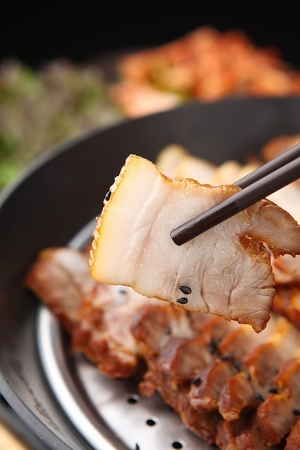 chopsticks holding Bossam, Korean cuisine, boiled pork wrapped in greensの写真素材