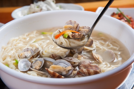 Clam noodles with zucchini and clams being scoopedの写真素材