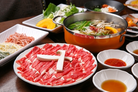 Shabu-shabu restuarant setting, with beef and vegetable platters, noodles and dipping saucesの写真素材