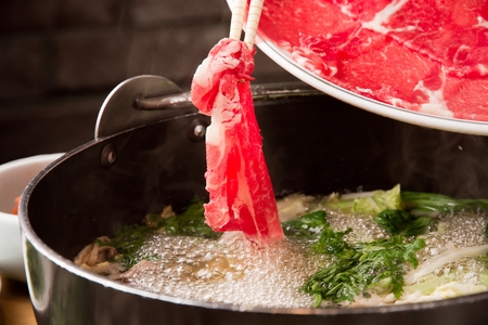 chopsticks putting beef in Shabu-shabu hot pot with bean sprouts, bok choy and vegetables in potの写真素材