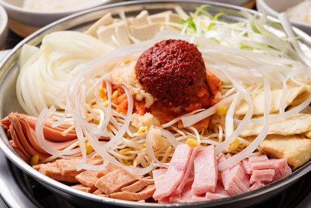Budae jjigae, spicy sausage stew with ham, noodles, fish cake and bean sprouts in fry panの写真素材