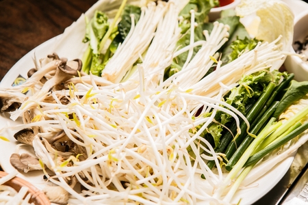 Shabu-shabu hot pot vegetables like mushroom, crown daisy and bok choy on plateの写真素材