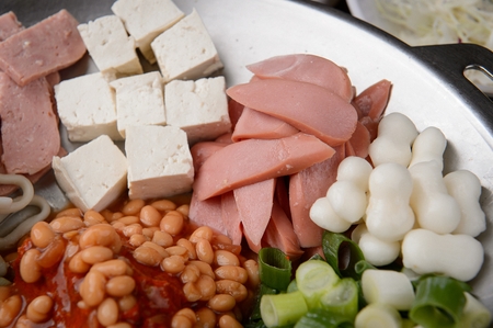 Budae jjigae, spicy sausage stew with ingredients like miced pork, tofu, ham, baked beans, rice cake...