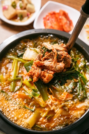 ladle scooping Korean cuisine Gamjatang, spicy pork back-bone stew with potato, mushroom and spring onion from potの写真素材