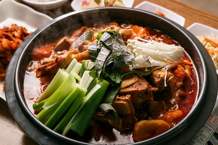 Korean cuisine Gamjatang, spicy pork back-bone stew with potato with vegetables on pot, served with various Ban-chan, side dishの写真素材