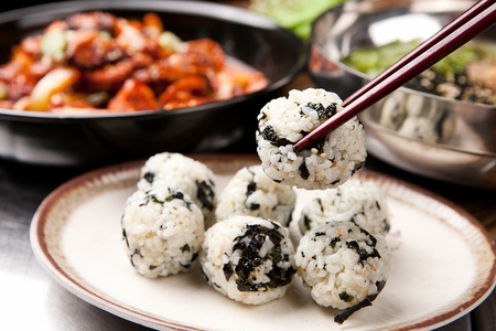 chopsticks holding Jumeok-bap, rice ball with dried seaweed from the plateの写真素材