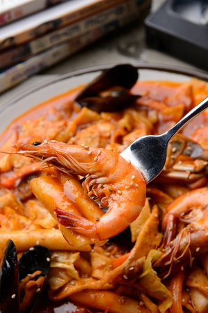 fork with shrimp from Haemul Tteok-bokki, stir-fried spicy seafood rice cake with shrimp and mussel on porcelain bowlの写真素材