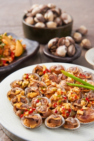 Kkomak muchim, blood cockle with soy sauce dressing made with onions and paprika on porcelain bowlの写真素材