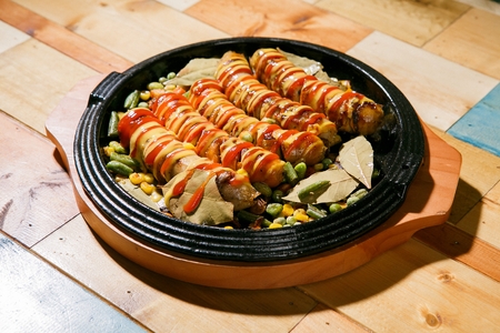 5 sausages with ketchup and mustard sauce on grill pan