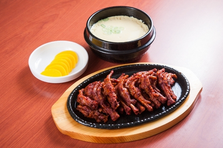 spicy grilled chicken feet on grill pan and steamed egg soup in Ttukbaegi, earthen potの写真素材