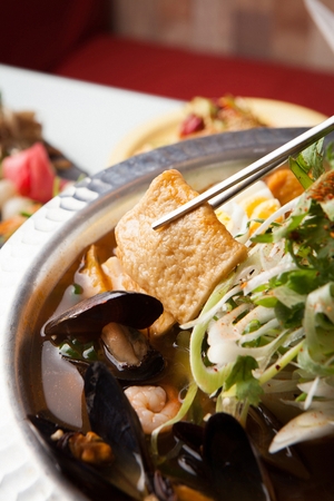 hot fish cake soup with mussels in metal bucketの写真素材