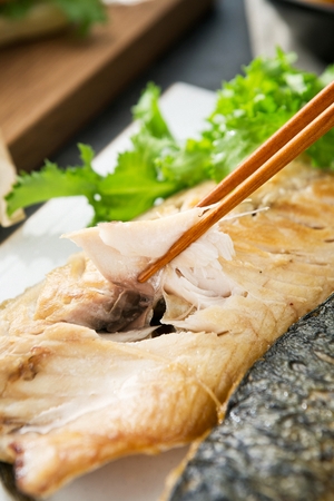 grilled mackerel sliced using chopsticks