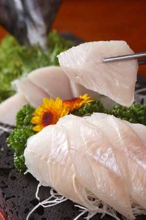 oily fish sashimi on chopsticksの写真素材