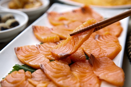salmon sashimi on chopsticksの写真素材