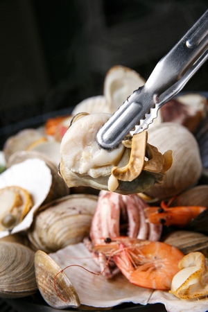 tongs holding clam from Jogae Jjim, steamed clams with vegetablesの写真素材
