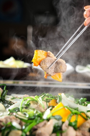 chopsticks holding grilled duck meat with vegetablesの写真素材