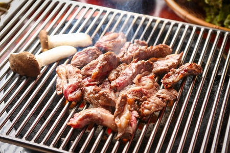 Beef being grilled on iron grateの写真素材