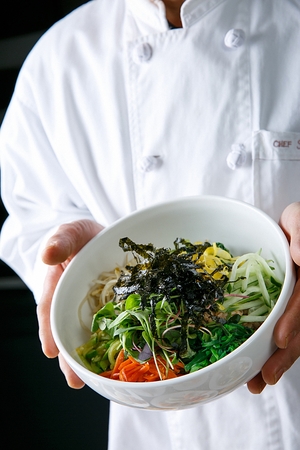 Hand picking up bowl with bibimbapの写真素材