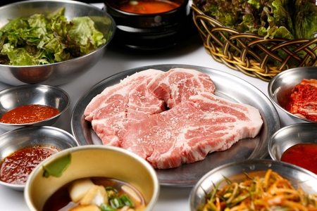 Raw pork neck on stainless plate with various side dishesの写真素材